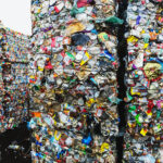Bales of compressed plastic bags and dairy product cartons at a recycling centre.